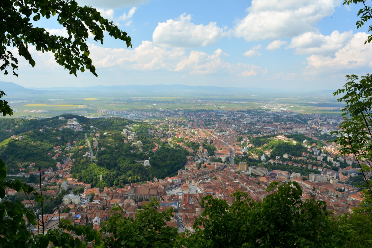 The Old Town and the Bârsa plain seen through trees from the wooded slopes above Brașov